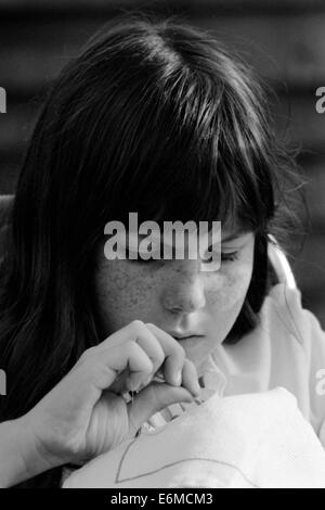 jeune fille se concentrant sur la couture dans le jardin early1980 royaume-uni Banque D'Images