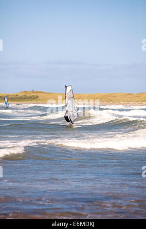 Planche à voile sur la plage de Cymyran, conseil informatique, Anglesey, au nord du Pays de Galles Banque D'Images