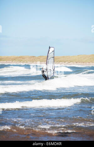 Planche à voile sur la plage de Cymyran, conseil informatique, Anglesey, au nord du Pays de Galles Banque D'Images