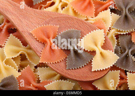 Pâtes farfalle tricolore dans une cuillère en bois. Banque D'Images