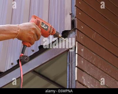 Carpenter à l'installation de verrouillage avec la perceuse électrique en construction Banque D'Images