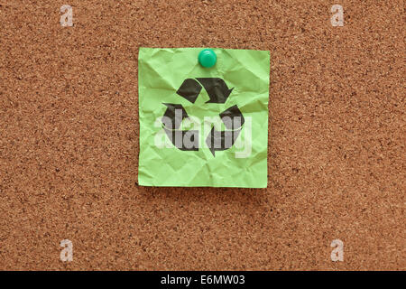 Note adhésive froissé vert avec symbole recyclage sur le panneau de liège (bulletin board). Banque D'Images