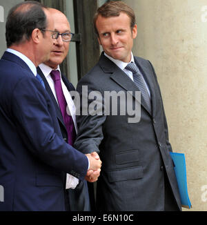 Paris, France. 27 août, 2014. Le Président français François Hollande (G) et de la France, de nouveau le ministre de l'économie, Emmanuel Macron (R) se serrer la main en tant que ministre français des finances Michel Sapin a l'air sur, comme ils laissent après la réunion hebdomadaire du cabinet à Paris, France, le 27 août, 2014. La France Secrétaire général de l'Elysée, Jean-Pierre Jouyet, a dévoilé mardi le nouveau gouvernement dirigé par le Premier ministre Manuel Valls, un jour après la démission de l'ancien gouvernement. Source : Xinhua/Alamy Live News Banque D'Images