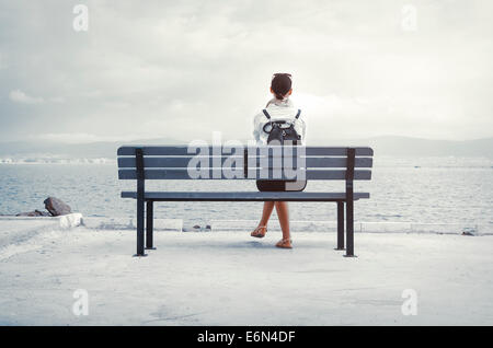 Femme seule assise sur un banc au bord de la mer Banque D'Images