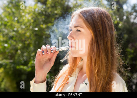 Jeune femme fumer une e-cigarette électronique Banque D'Images