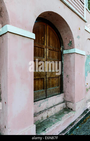 Lambris en bois ancien, un ensemble de portes extérieures en vertu d'une entrée voûtée d'un bâtiment en stuc à Frederiksted, îles Vierges américaines. Banque D'Images