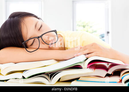 Fille à lunettes étudiant fatigué de dormir sur les livres avec arrière-plan de la salle Banque D'Images