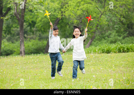 Heureux les enfants tenant les mains jouant sur l'herbe Banque D'Images
