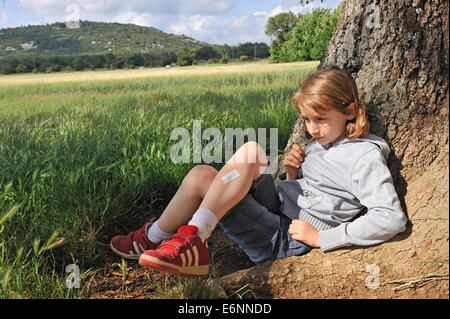 Petite fille (9 ans) réflexion assis sous un arbre Banque D'Images