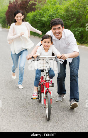 L'enseignement aux jeunes parents fille monter à vélo Banque D'Images