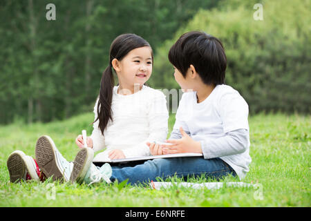 Garçon et fille s'appuyant sur l'herbe Banque D'Images