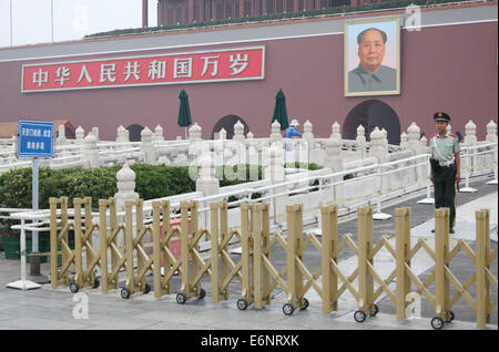 Un garde de sécurité, devant une photo de Mao Zedong, ancien président du parti communiste et président de la Chine sur la place Tiananmen à Beijing, Chine, 04 juillet 2014. Photo : Friso Gentsch/dpa Banque D'Images
