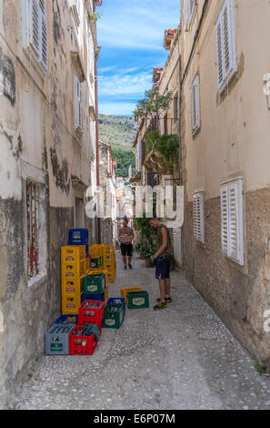 Deux jeunes hommes transporter et empiler des caisses de bière en bouteille dans une rue dans la vieille ville de Dubrovnik. Banque D'Images