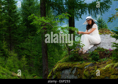 Femme en robe blanche avec white hat restant sur une grosse pierre dans la montagne Banque D'Images