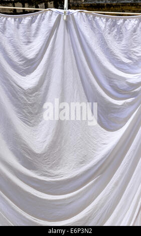 Des draps blancs suspendus feuilles à sécher sur un lave-ligne. Banque D'Images