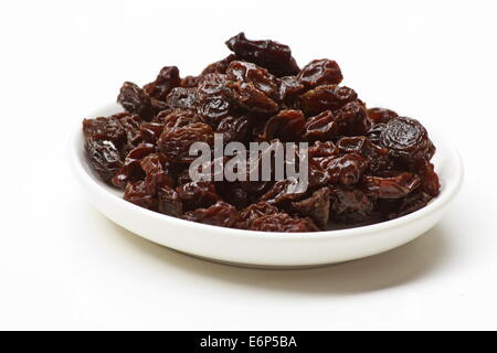 Les raisins secs dans un plat blanc sur fond blanc Banque D'Images