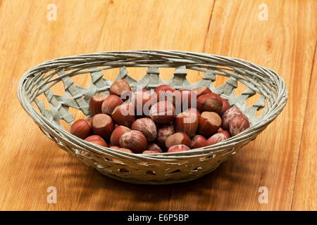 Les noisettes dans un panier vert sur une table en bois Banque D'Images