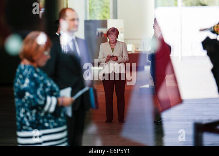 Berlin, Allemagne. 28 août, 2014. La chancelière allemande Angela Merkel utilise son téléphone portable pendant qu'elle attend l'arrivée des participants pour la 'Conférence des Balkans de l'Ouest" à la chancellerie à Berlin, jeudi, 28 août, 2014. Merkel a invité pour la conférence d'appui à la situation économique et politique dans la région de l'Europe du Sud-Est. Photo : Markus Schreiber/dpa Banque D'Images