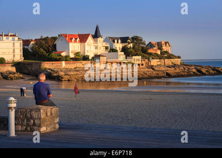 Homme assis sur le mur bénéficiant du soleil du soir à Conche de Saint Palais près de Royan. Banque D'Images