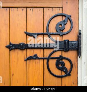 Close up d'une charnière de porte en fer peint en noir sur une porte en bois. Banque D'Images