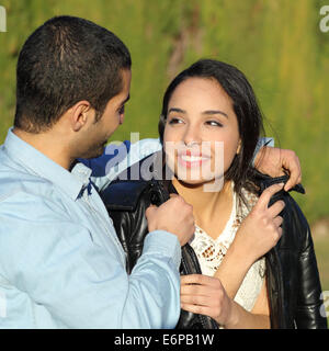 Heureux couple flirting arabe tout en représentant son avec sa veste dans un parc avec un fond vert Banque D'Images