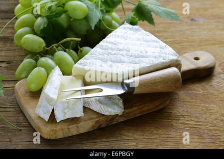 Fromage brie doux avec de doux raisins sur une planche en bois Banque D'Images