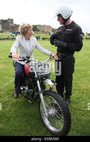 Peak District, Derbyshire, Royaume-Uni. 29 août 2014. La duchesse de Devonshire fait l'essai d'une moto 750cc Triumph appartenant aux signaux Royal Moto Casques blancs de l'équipe d'affichage comme elle s'entretient de ses fonctions habituelles, le sergent de l'équipe cycliste Marshall Stevie pendant le premier jour de l'assemblée annuelle tenue foire du comté de Chatsworth dans le parc entourant la maison seigneuriale du Derbyshire. L'événement de trois jours soit jusqu'au dimanche 31 août. Credit : Matthew Taylor/Alamy Live News Banque D'Images