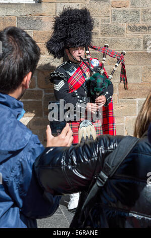 Les touristes de prendre une photo d'un Piper à l'aide d'un téléphone mobile sur le Royal Mile, Édimbourg Banque D'Images