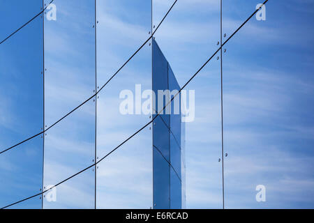 Des panneaux de verre sur la façade du bâtiment de commerce en raison de ciel bleu et nuages Banque D'Images