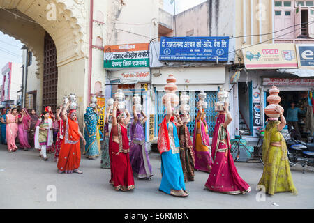 Procession traditionnelle de mariage à Deogarh, Rajasthan, Inde: Les femmes locales vêtues de saris colorés portent des pots sur leur tête Banque D'Images