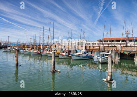 Bateaux à Fisherman's Wharf, San Francisco, sous un ciel bleu plein de traînées de condensation. Banque D'Images