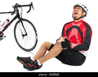 Cycliste asiatique est tombé de vélo à l'articulation du genou blessé, douleur à l'expression du visage et assis sur le plancher, isolé sur blanc bac Banque D'Images