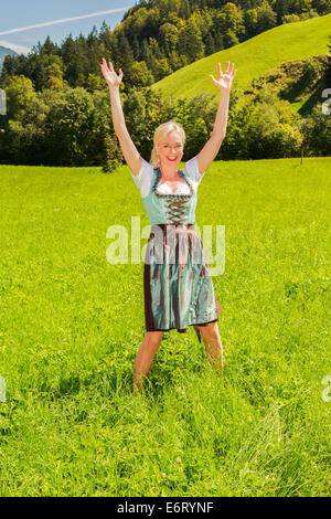 Femme blonde dans un dirndl est heureux dans un pré vert Banque D'Images