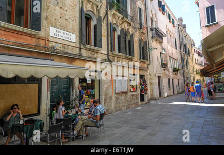 Les habitants et les touristes à profiter d'un café à l'extérieur dans les nombreuses rues étroites de Venise, Italie Banque D'Images