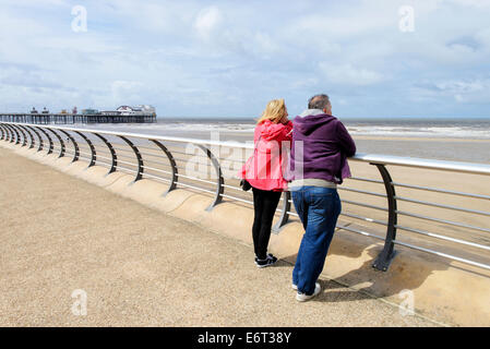 Couple d'âge moyen sur la promenade de Blackpool face à la mer. North Pier est à l'arrière-plan Banque D'Images