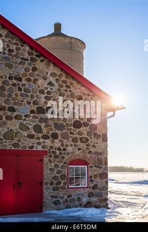 Ancienne grange en pierre vers 1903. Scène d'hiver. La lumière du soleil chaud et bien arrondi. Porte et fenêtre rouge vif avec brique arch. Banque D'Images