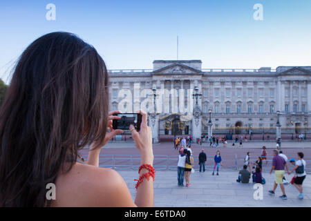 Une jeune femme de prendre une photo de Buckingham Palace, sur son téléphone portable Banque D'Images