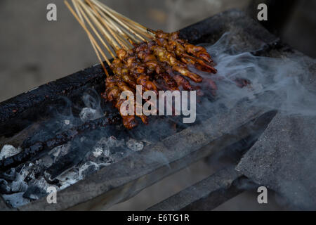 Yogyakarta, Java, Indonésie. L'alimentation de rue. Brochettes de poulet satay de poulet, ou sur le gril, un feu de charbon. Banque D'Images