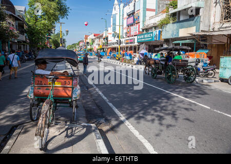 Yogyakarta, Java, Indonésie. La rue Malioboro, tôt le matin, Les Becak (Man-tricycle rickshaw) et alimenté en calèche. Banque D'Images