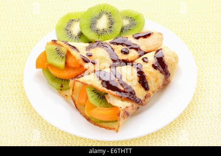 Crêpes avec kiwi et tranches d'abricots on white plate Banque D'Images