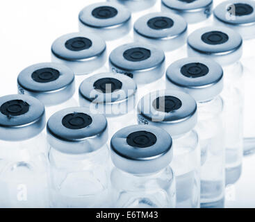 Flacons en verre avec la médecine botox, collagène, hualuronic sur un fond bleu et blanc. Banque D'Images