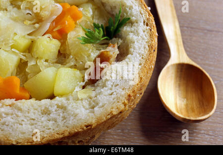 La soupe aux choux dans une miche de pain sur une table en bois Banque D'Images