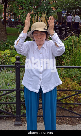 Une vieille femme chinoise Falun Dafa en exercices pratiques Suare Union Park à New York. C'est la position debout de Falun. Banque D'Images