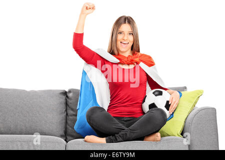 Fan de sport féminin cheering assis sur un canapé isolé sur fond blanc Banque D'Images