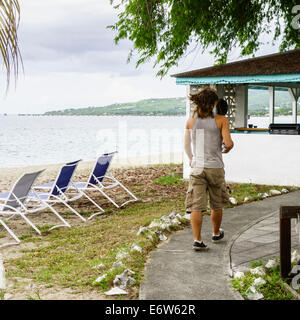 Un jeune homme en cargo shorts et T-shirt de muscle s'approche d'un resort cabana sur la plage de Sainte Croix, îles Vierges américaines. Cottages by the Sea Resort Banque D'Images