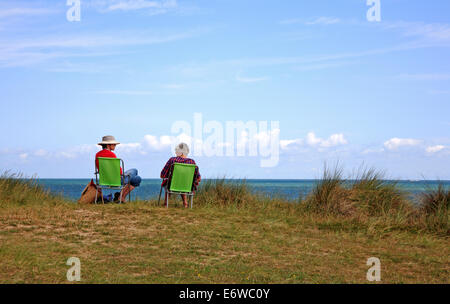 Deux dames assis sur des chaises dans les dunes de sable donnant sur la mer à Winterton, Norfolk, Angleterre, Royaume-Uni. Banque D'Images