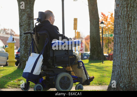 L'homme avec la moelle épinière et le bras de lésions nerveuses en fauteuil roulant motorisé dans un parc public Banque D'Images