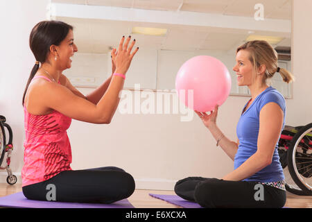 Les jeunes femmes ayant une lésion de la moelle épinière en jouant avec une boule d'exercice Banque D'Images