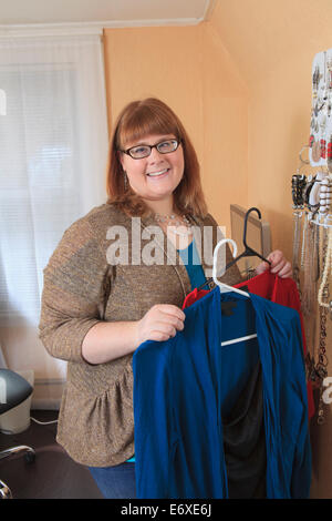 Femme qui est aveugle au sens de la cueillette à robes de porter dans sa maison. Banque D'Images