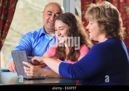 Fille avec père et mère à l'aide de comprimés et en s'amusant Banque D'Images
